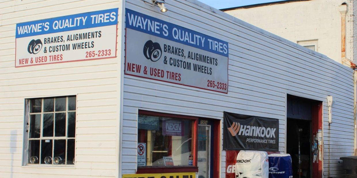 Exterior of Wayne's Quality Tires shop with visible signs and tires outside.