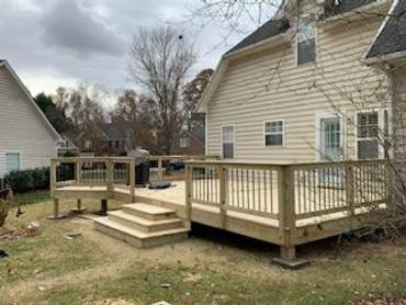 Newly built wooden deck attached to a house with steps leading down to the yard.