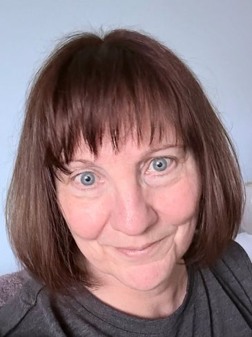 Woman with short brown hair and blue eyes smiling.