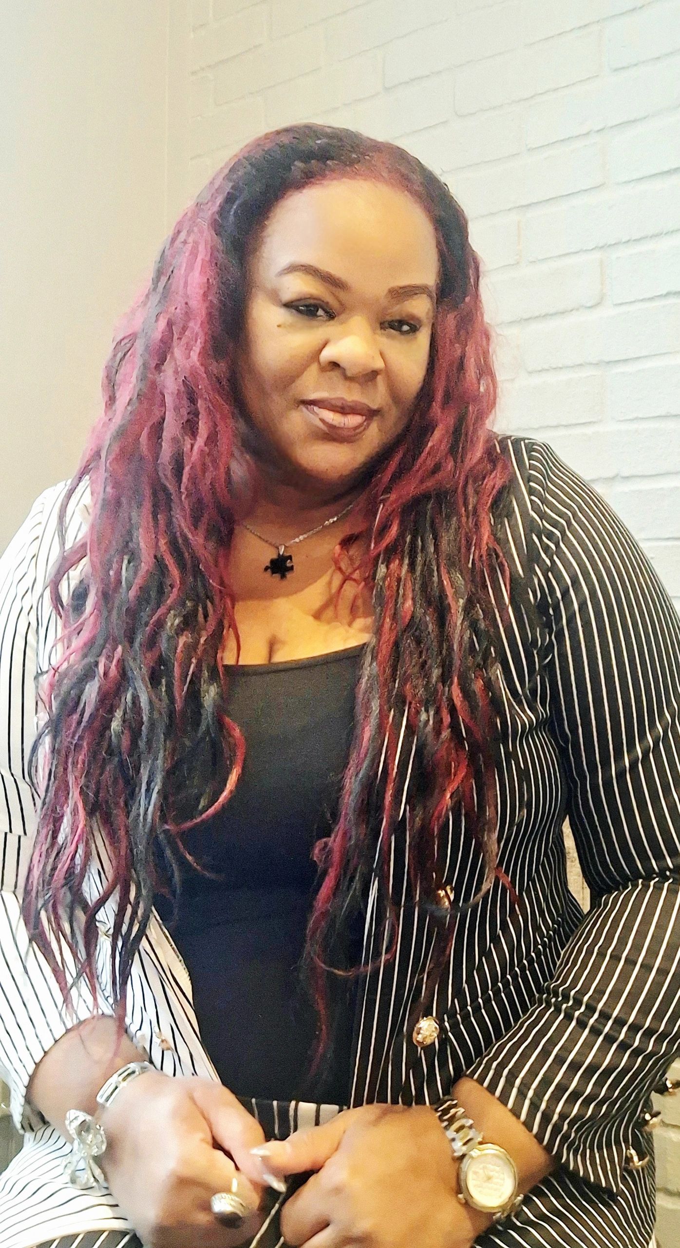 Woman with long red and black hair in a striped blazer.