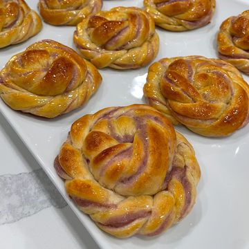 Golden brown twisted buns with a shiny glaze on a white plate.