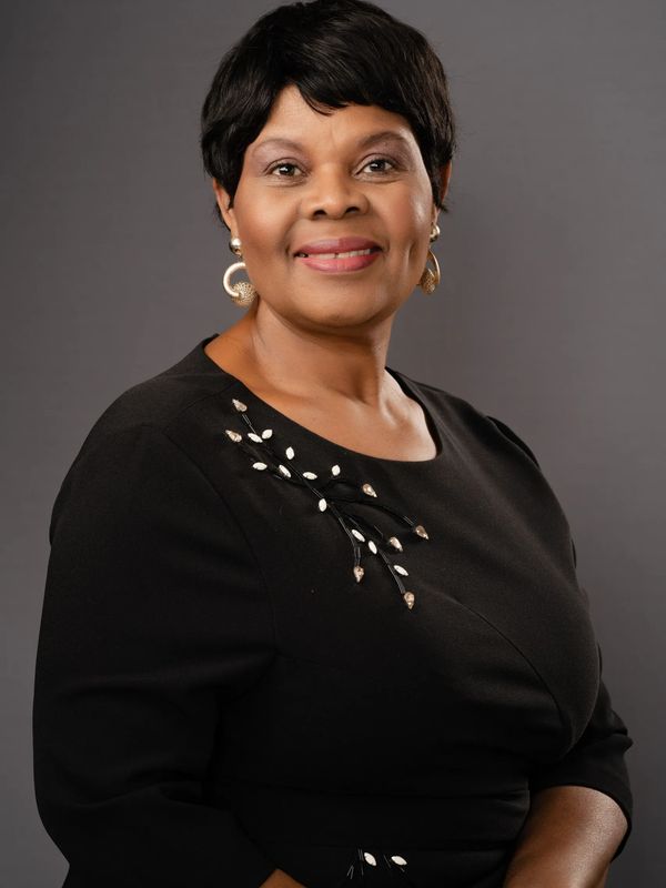 A photo of Dr. Joyce Nyirenda, DBH, LCMHC in a brown shirt