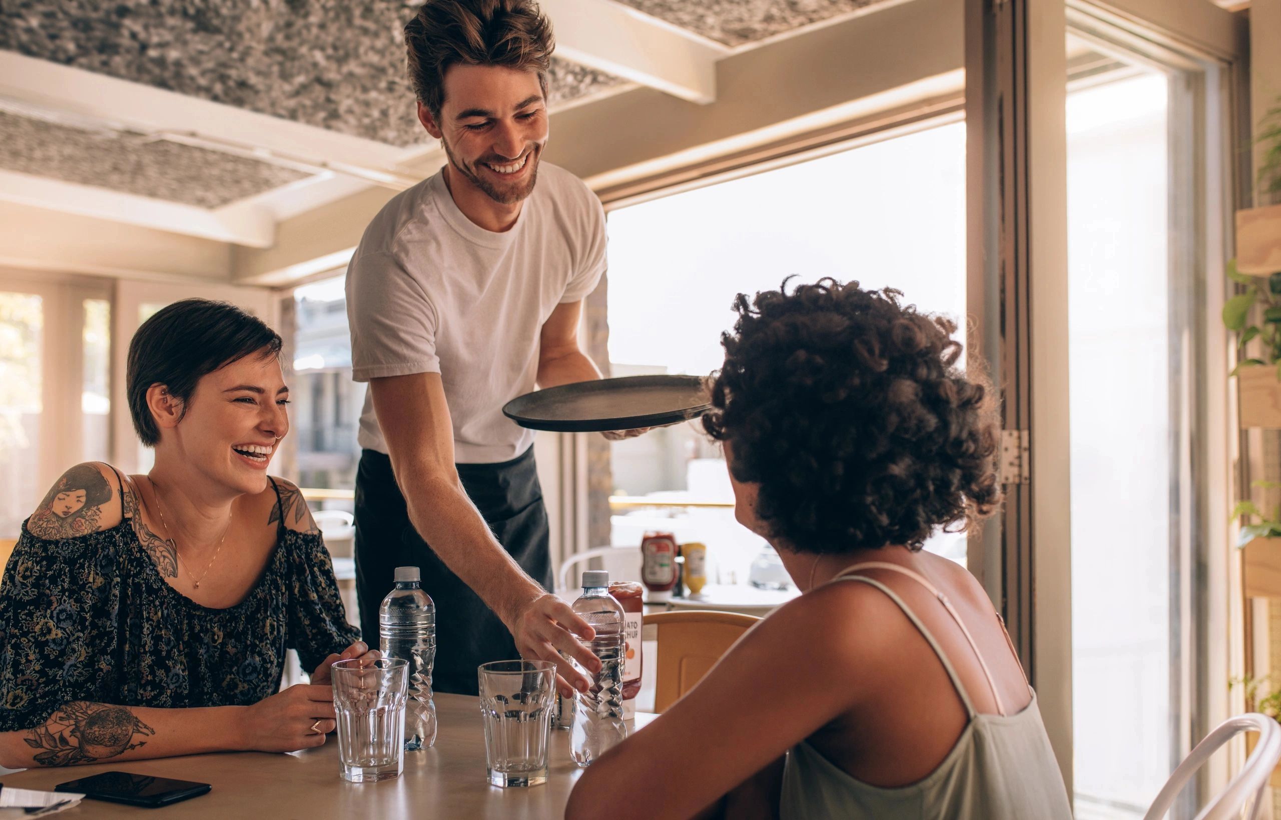 A food handler serving a customer at a table in a restaurant.