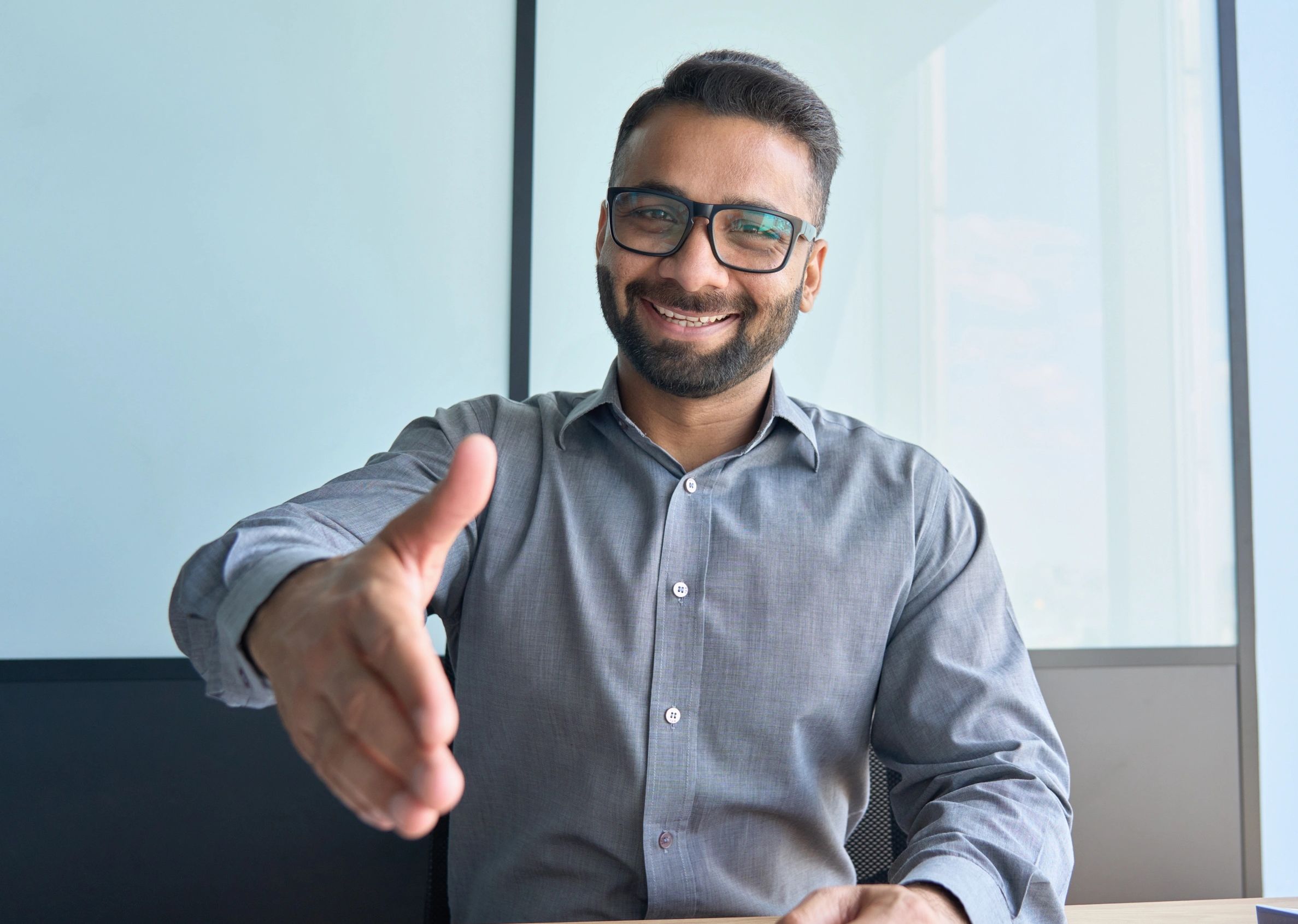 A member of the greeting staff warmly shaking hands with a visitor.