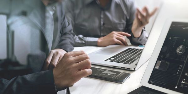 Two people working on laptops at a desk.