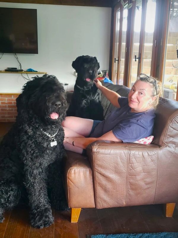 Carol Ann Moore with two Black Russian Terriers sitting on a leather sofa
