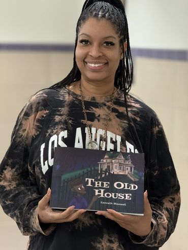 Woman smiling and holding a book titled "The Old House" by Kenneth Maxwell.