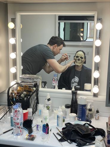 Prosthetic makeup application process. Foam latex skull being applied to a cast member.