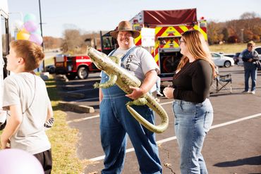 A man in overalls with a blow up gator at Champion Life Church Cajun Gras in 2024