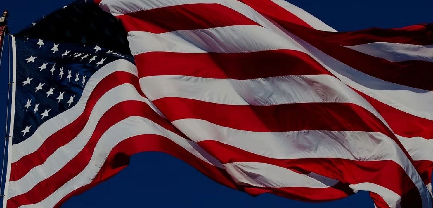 The American flag waving against a clear blue sky.