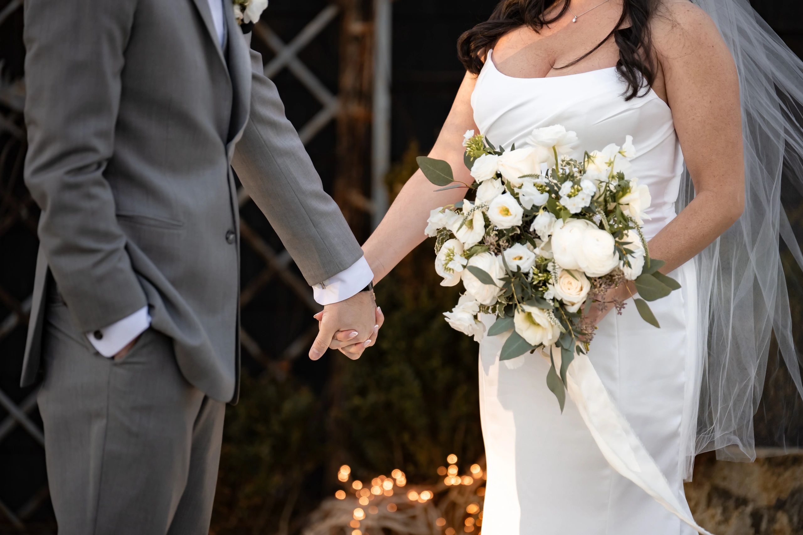 Bride and groom holding hands, bride holding a beautiful white flower bouquet.