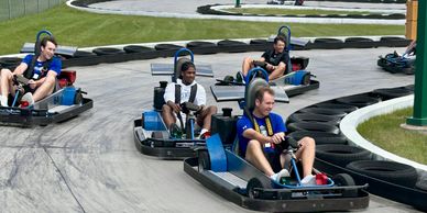Four people racing go-karts on an outdoor track.