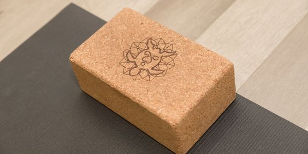 A cork yoga block with the Sangha Center for Yoga and Wellness turtle logo.