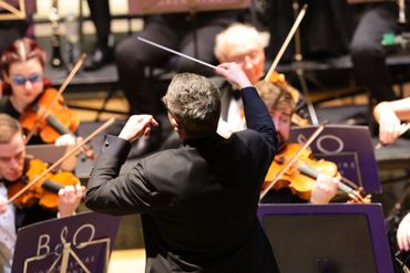 Conductor leading an orchestra during a live performance.