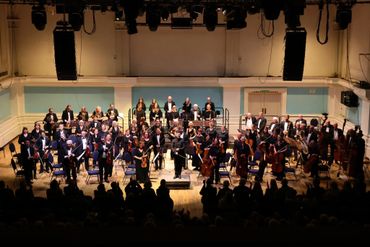Full orchestra takes a bow on stage after a performance.