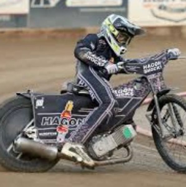 Motorcycle racer in black gear speeding on dirt track.