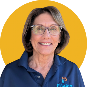 Smiling woman in glasses and a blue Pharos shirt against a yellow background.