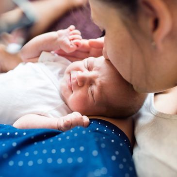 Woman kissing newborn forehead.
