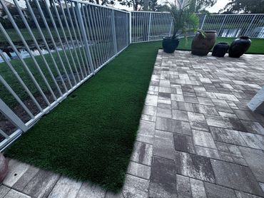 Natural looking HFX natural turf with gray stone pavers . Perfect match for a modern back yard look