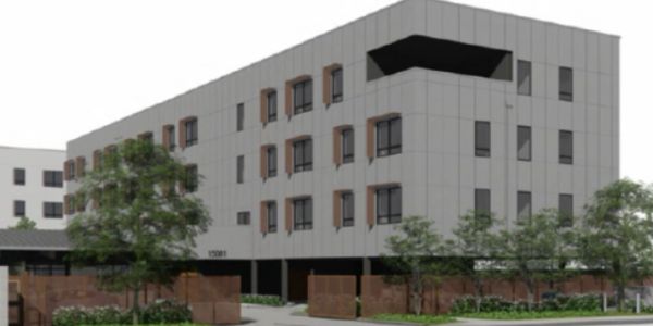 Modern four-story building with trees and shrubs.