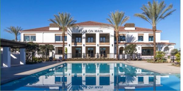 Modern clubhouse with pool and palm trees under clear blue sky.