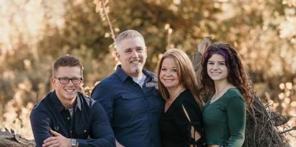 A happy family of four posing outdoors in autumn.