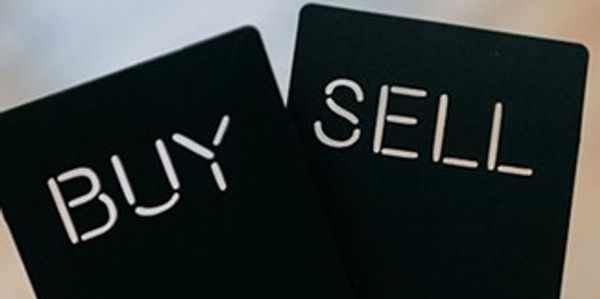 Two black cards with the words BUY and SELL held in a hand.