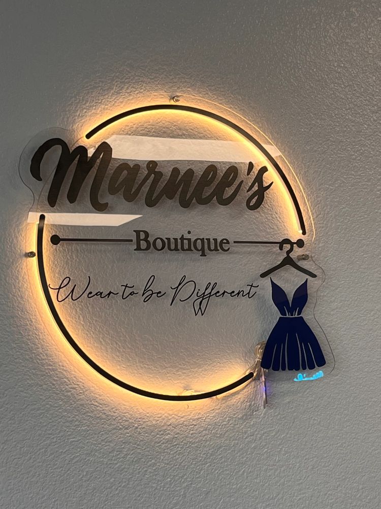 Illuminated sign for Marnee's Boutique with the slogan 'Wear to be Different'. Featuring a dress
