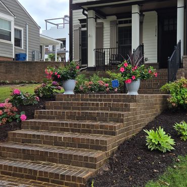 Brick steps leading to a house with colorful flowers and neatly landscaped garden.
