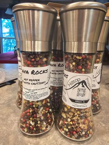 Glass spice grinders filled with colorful hot pepper flakes labeled 'Lava Rocks'.