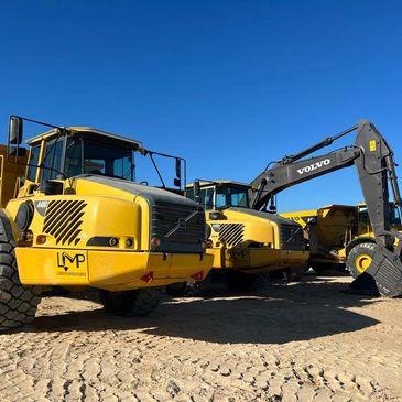 Yellow Volvo construction vehicles under clear blue sky.
