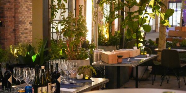 Elegant outdoor dining setup with wine bottles and glassware amidst lush greenery.