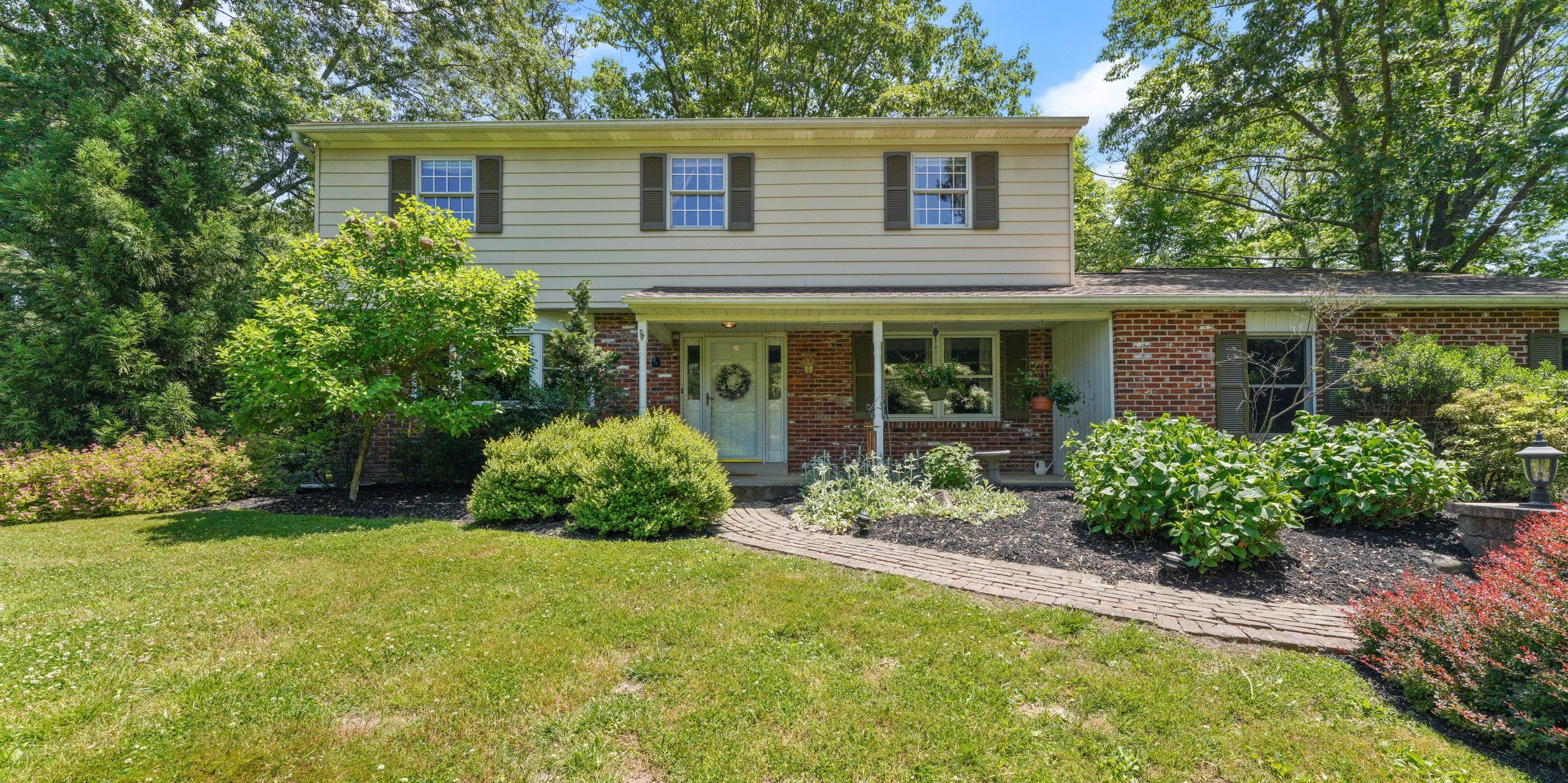 A two-story house with a garden and brick walkway.