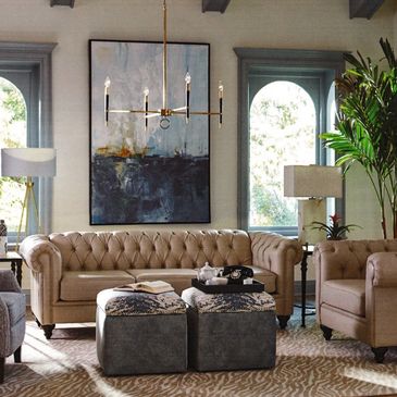 Elegant living room with beige tufted sofas, modern lighting, and large green plant.