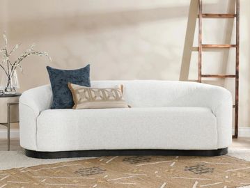 Modern white sofa with decorative pillows in a cozy living room.