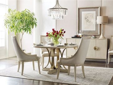 Elegant dining room with beige chairs, a round table, and a vase of red tulips.