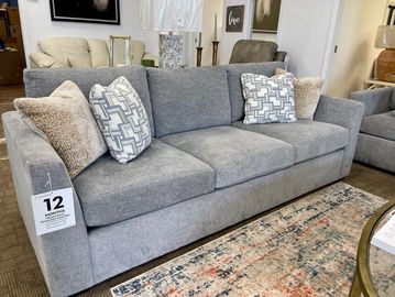 Modern gray sofa with patterned and textured cushions in a showroom.
