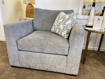 Modern gray armchair with a patterned cushion in a cozy room.