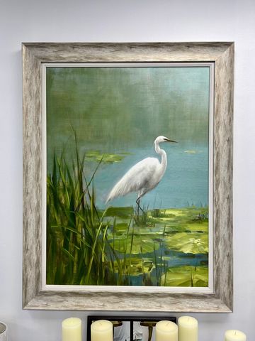 Painting of a white heron standing in a pond with lily pads and reeds.
