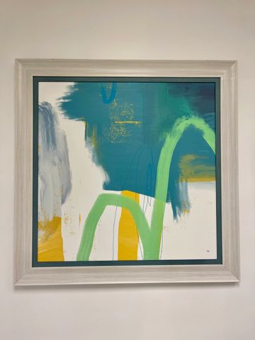 Abstract painting with green, blue, yellow, and white colors in a light wooden frame.
