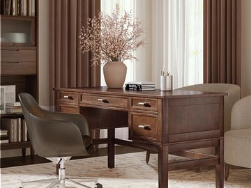 Elegant wooden desk with a vase of flowers and a leather office chair in a cozy room.