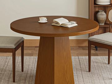 Round wooden dining table with a cup of coffee and an open book.