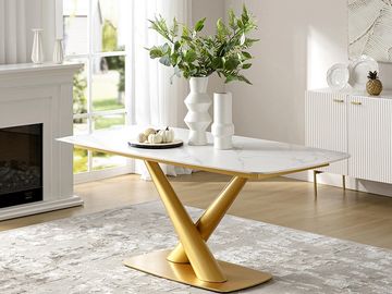 Modern white and gold coffee table with decorative vases and greenery in a bright living room.
