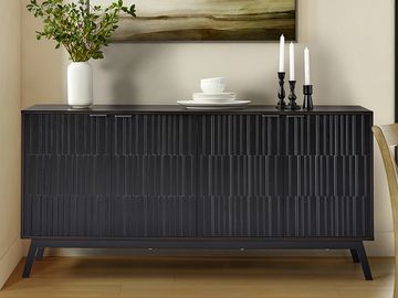 Black textured sideboard with decorative vase, dishes, and candles in a modern room.