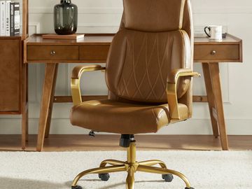 Brown leather office chair with gold accents in a stylish workspace.