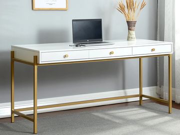Modern white desk with golden legs, laptop, and vase with dried flowers.