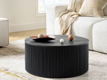 Round black coffee table with decorative balls in a cozy living room.