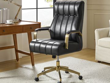 Black leather office chair with gold armrests and base on a white rug.
