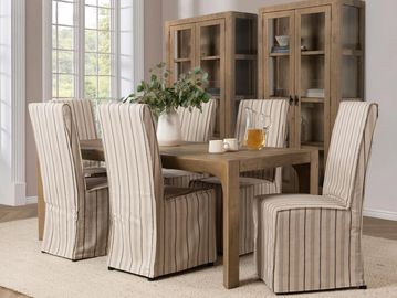 Rustic dining room with wooden table, striped slipcovered chairs, and glass cabinets.