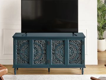 Blue TV stand with intricate floral carvings under a flat-screen TV.
